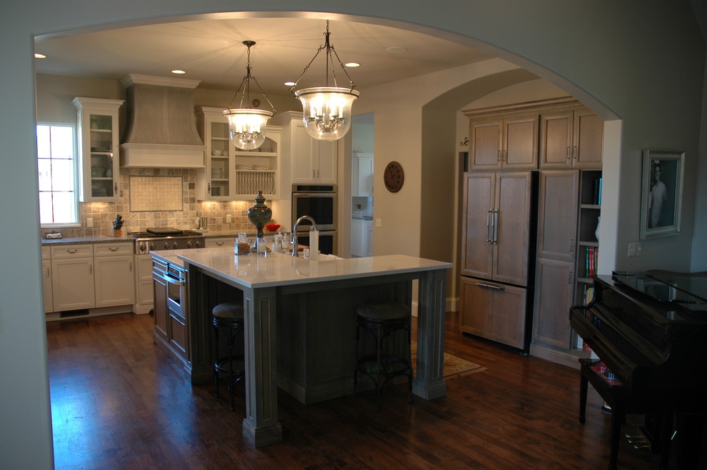 Example of a large transitional u-shaped medium tone wood floor kitchen pantry design with a farmhouse sink, flat-panel cabinets, yellow cabinets, laminate countertops, brown backsplash, stone tile backsplash, paneled appliances and an island
