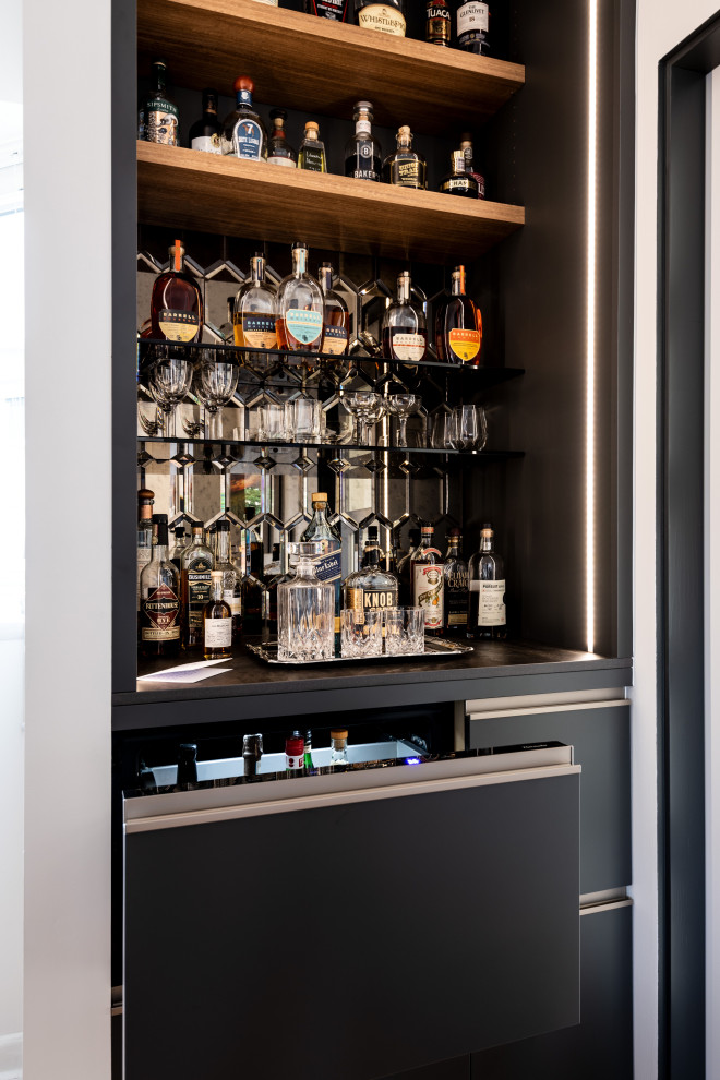 This is an example of a small modern single-wall home bar in Seattle with flat-panel cabinets, mirror splashback and black cabinets.