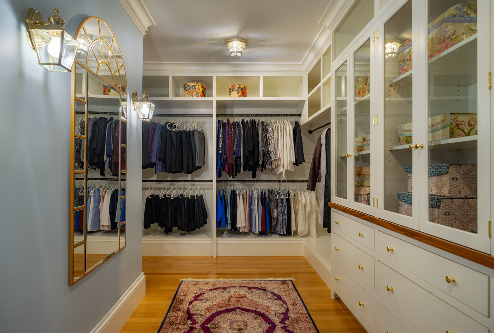 This is an example of a traditional gender-neutral walk-in wardrobe in Boston with flat-panel cabinets, white cabinets, medium hardwood floors and brown floor.