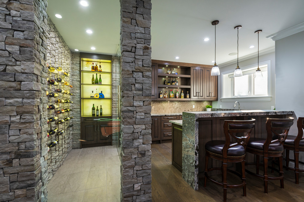 Design ideas for a large traditional single-wall seated home bar in Vancouver with raised-panel cabinets, brown cabinets, granite benchtops, brown splashback, porcelain splashback, medium hardwood floors, brown floor and brown benchtop.