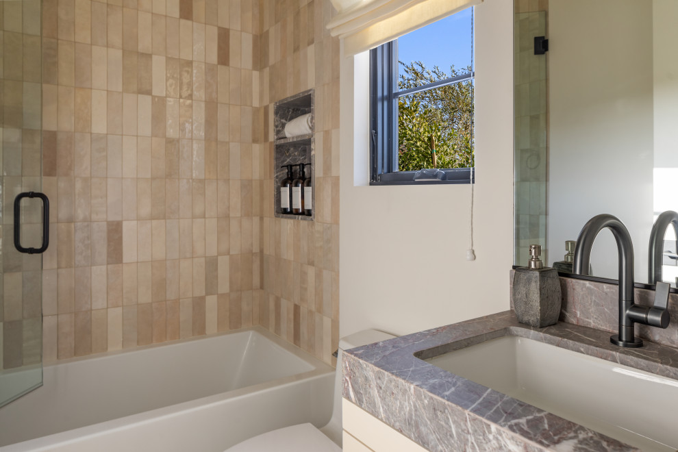 Idéer för att renovera ett mellanstort brun brunt badrum med dusch, med släta luckor, bruna skåp, ett badkar i en alkov, en dusch/badkar-kombination, en toalettstol med hel cisternkåpa, beige kakel, perrakottakakel, vita väggar, ett undermonterad handfat, marmorbänkskiva och dusch med gångjärnsdörr