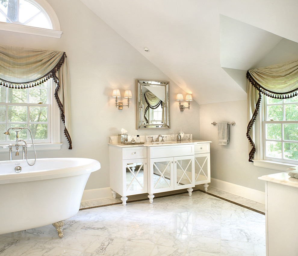 Design ideas for a mid-sized contemporary master bathroom in New York with a claw-foot tub, stone tile, white tile, an undermount sink, marble benchtops, furniture-like cabinets, grey walls, white cabinets, marble floors and multi-coloured floor.