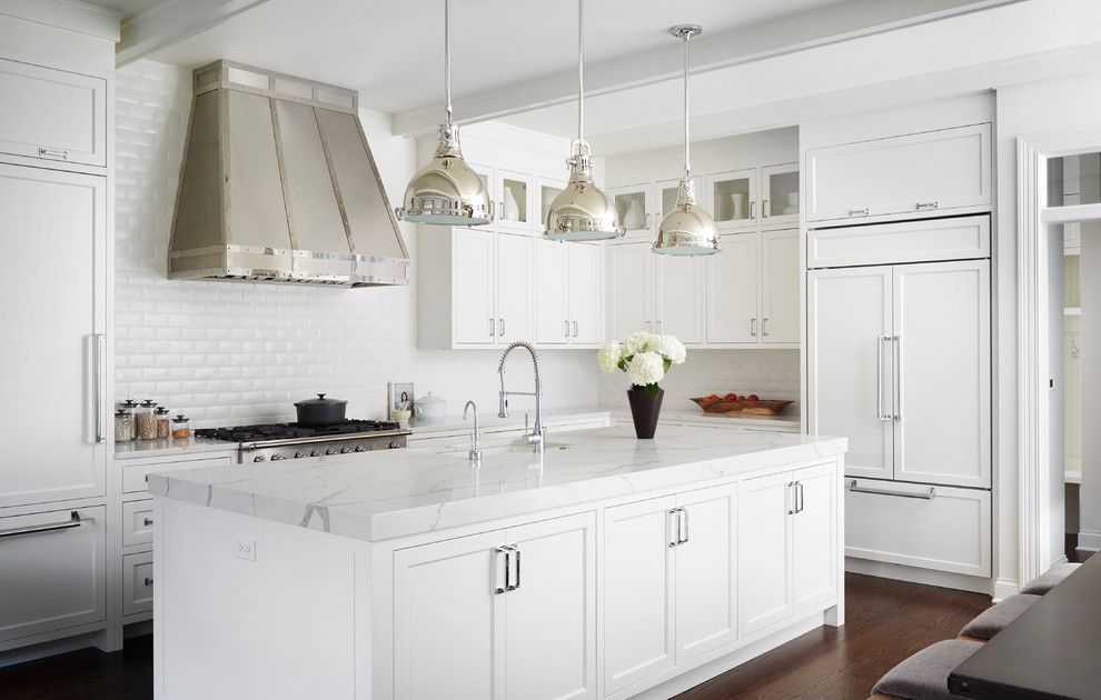 Photo of a large transitional l-shaped kitchen in Chicago with shaker cabinets, white cabinets, marble benchtops, white splashback, subway tile splashback, dark hardwood floors, with island, panelled appliances and a single-bowl sink.