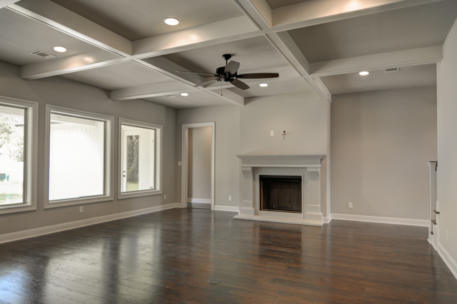 Photo of a mid-sized traditional formal open concept living room in Austin with beige walls, dark hardwood floors, a standard fireplace, a concrete fireplace surround and a wall-mounted tv.