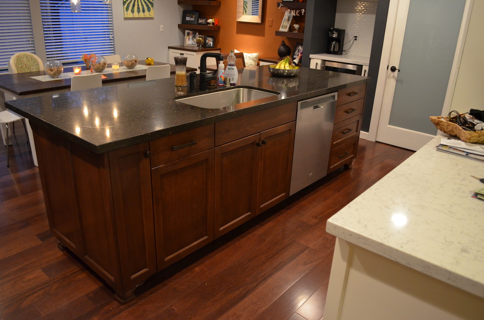 Trendy dark wood floor kitchen photo in Sacramento with an undermount sink, recessed-panel cabinets, dark wood cabinets, stainless steel appliances and an island