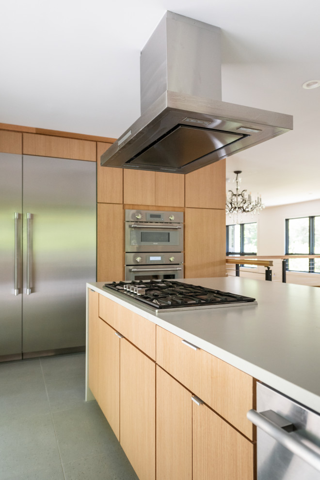 Inspiration for a large contemporary medium tone wood floor eat-in kitchen remodel in DC Metro with a single-bowl sink, flat-panel cabinets, light wood cabinets, solid surface countertops, black backsplash, stone tile backsplash, stainless steel appliances, an island and white countertops