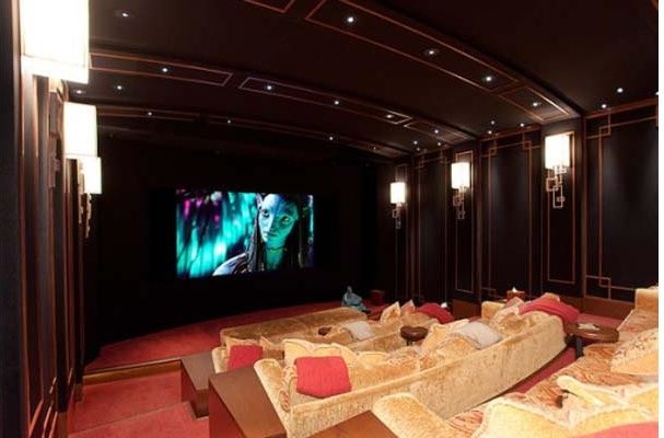 This is an example of a mid-sized traditional enclosed home theatre in Vancouver with brown walls, carpet and a projector screen.
