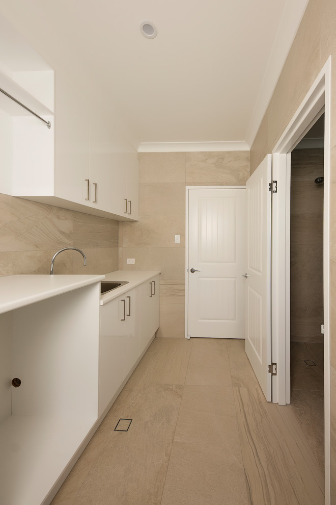 Photo of a small contemporary single-wall dedicated laundry room in Brisbane with a single-bowl sink, flat-panel cabinets, white cabinets, laminate benchtops, beige walls, ceramic floors, a side-by-side washer and dryer and beige floor.