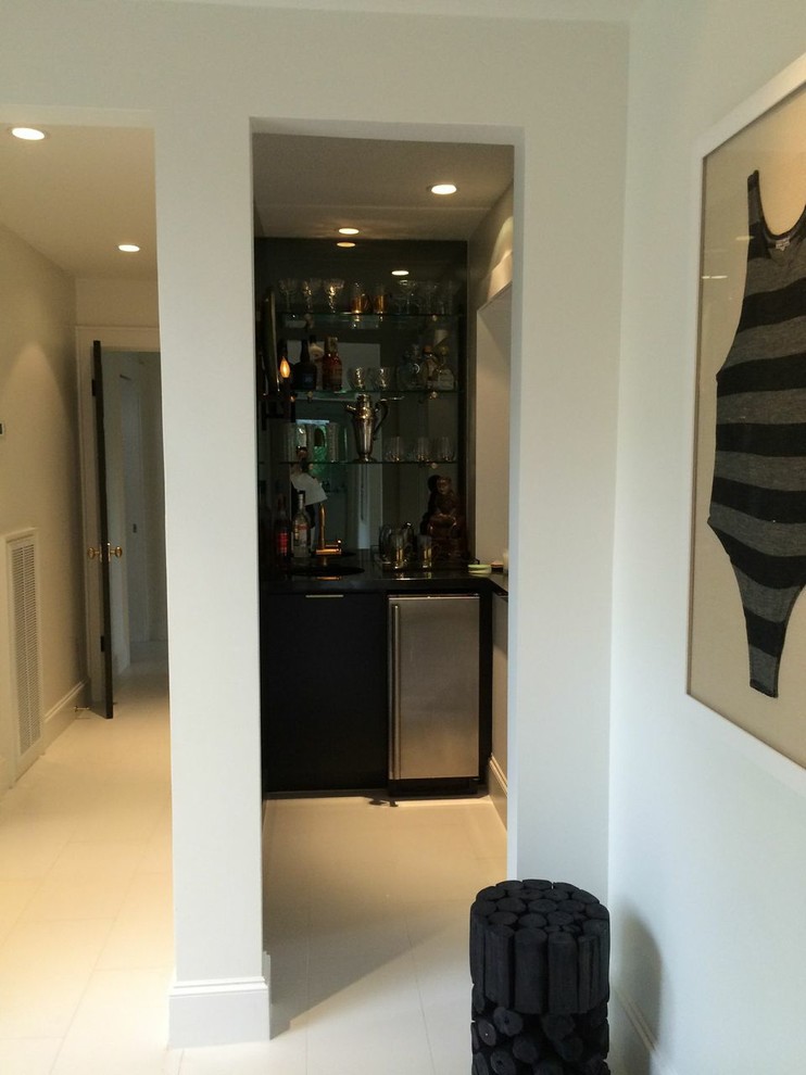 Photo of a small transitional l-shaped wet bar in Houston with flat-panel cabinets, black cabinets, ceramic floors and quartzite benchtops.