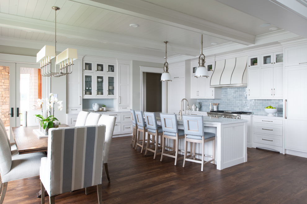 Photo of a mid-sized country l-shaped eat-in kitchen in Minneapolis with dark hardwood floors, a farmhouse sink, shaker cabinets, white cabinets, marble benchtops, blue splashback, subway tile splashback, panelled appliances, with island, brown floor and white benchtop.
