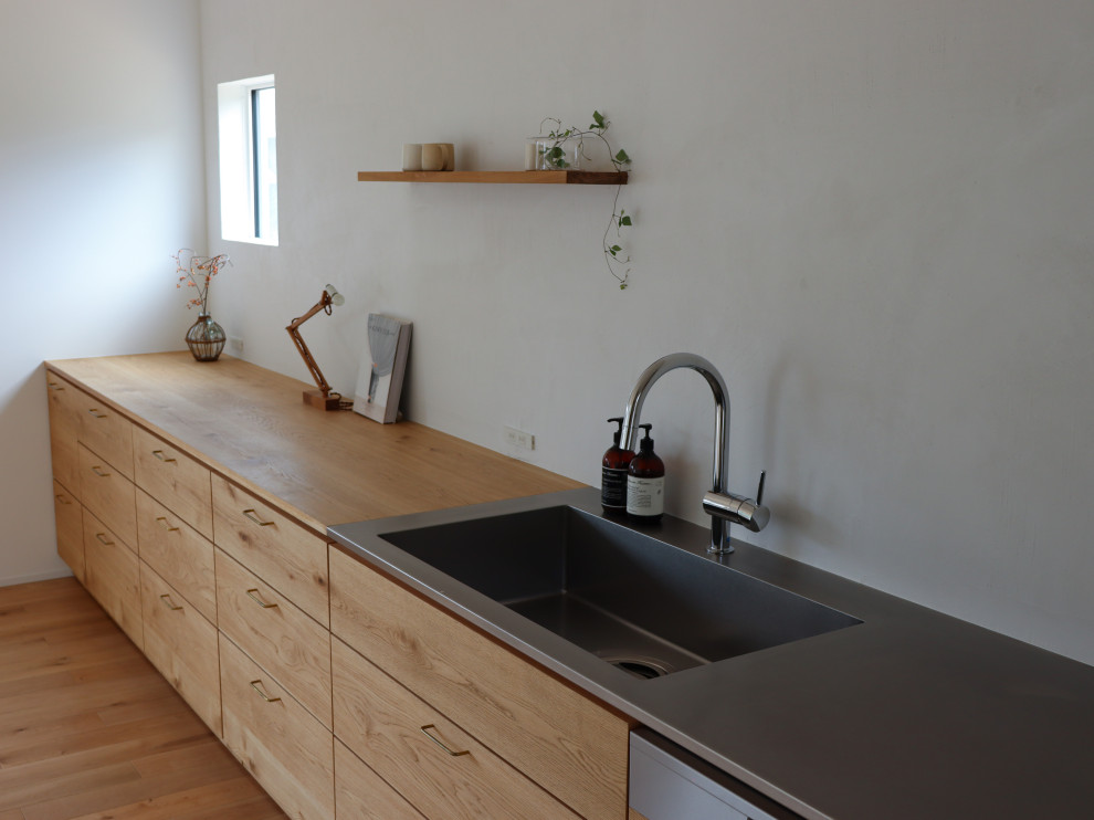 Réalisation d'une cuisine ouverte linéaire minimaliste de taille moyenne avec un évier intégré, un plan de travail en inox, parquet clair, aucun îlot et un plafond en papier peint.