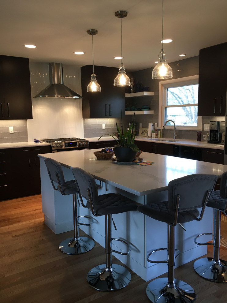 Mid-sized contemporary l-shaped eat-in kitchen in Indianapolis with an undermount sink, flat-panel cabinets, dark wood cabinets, quartz benchtops, grey splashback, porcelain splashback, stainless steel appliances, light hardwood floors, with island and brown floor.