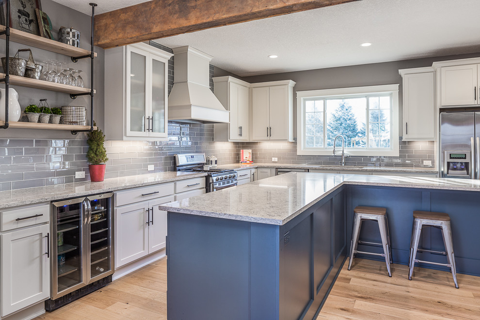 Eat-in kitchen - large transitional l-shaped eat-in kitchen idea with white cabinets, quartzite countertops, gray backsplash, glass tile backsplash, stainless steel appliances and an island