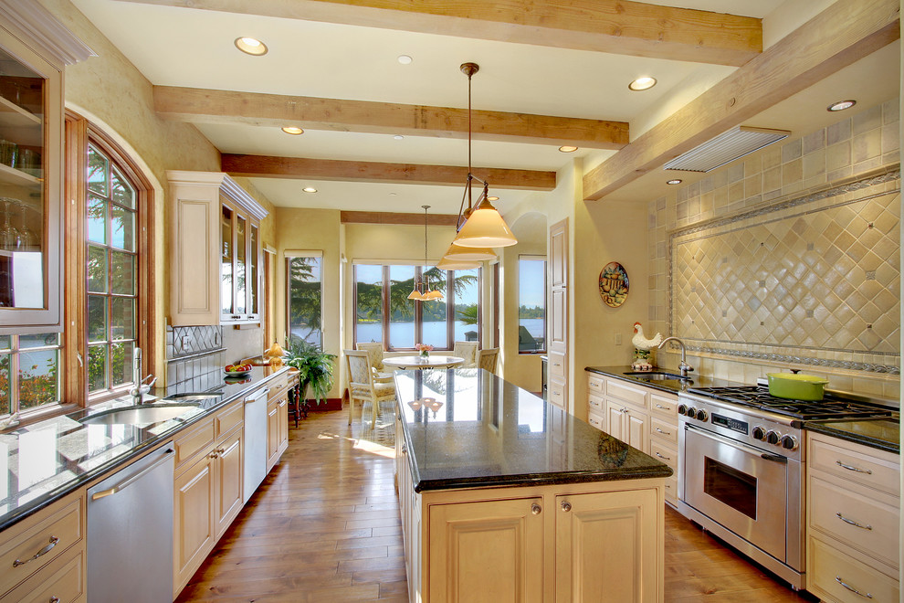Inspiration for a large traditional galley eat-in kitchen in Seattle with an undermount sink, recessed-panel cabinets, light wood cabinets, granite benchtops, beige splashback, ceramic splashback, stainless steel appliances, medium hardwood floors and with island.