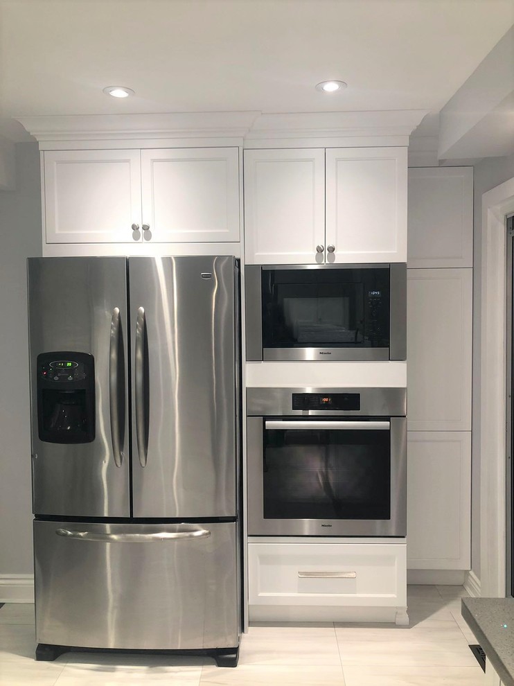 This is an example of a small modern u-shaped separate kitchen in Toronto with a single-bowl sink, shaker cabinets, white cabinets, quartz benchtops, grey splashback, porcelain splashback, stainless steel appliances, ceramic floors, white floor and grey benchtop.