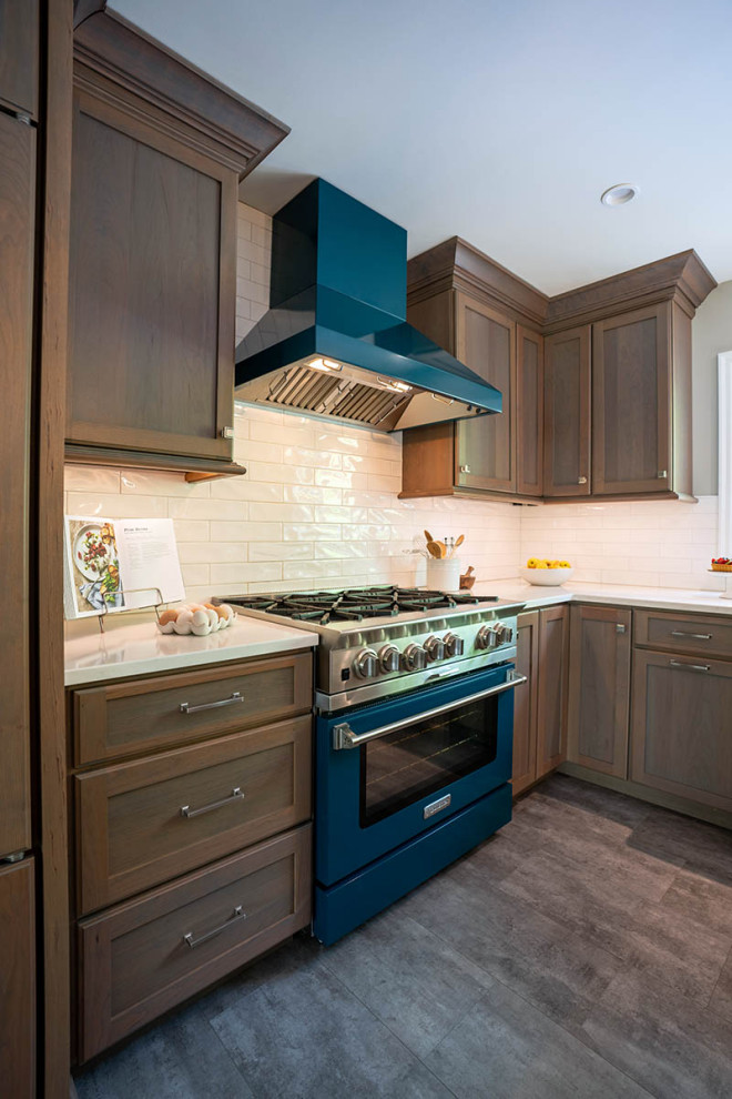 This is an example of a medium sized contemporary l-shaped kitchen/diner in Philadelphia with a belfast sink, shaker cabinets, dark wood cabinets, engineered stone countertops, white splashback, metro tiled splashback, integrated appliances, vinyl flooring, an island, grey floors and grey worktops.