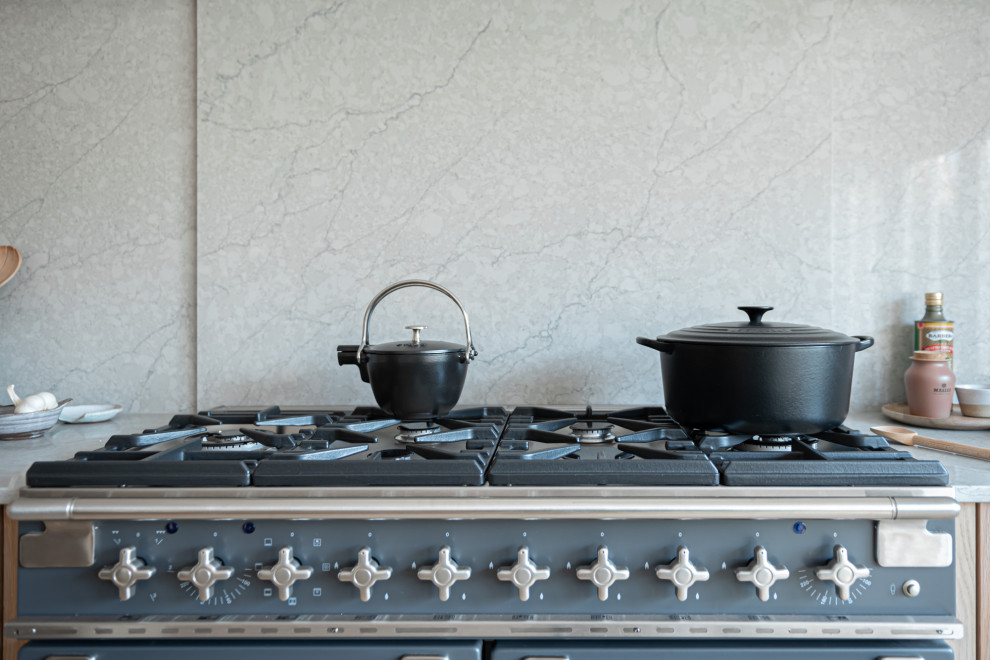 Ispirazione per una grande cucina scandinava con lavello integrato, ante in stile shaker, ante in legno chiaro, top in quarzite, paraspruzzi grigio, elettrodomestici neri, parquet chiaro e top grigio