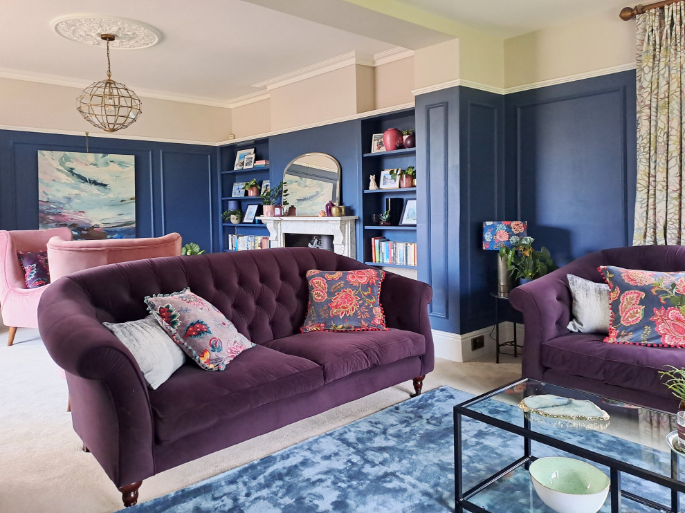 This is an example of a large victorian formal and grey and pink enclosed living room in Hampshire with blue walls, carpet, a wood burning stove, a stone fireplace surround, a freestanding tv, grey floors, panelled walls and a dado rail.