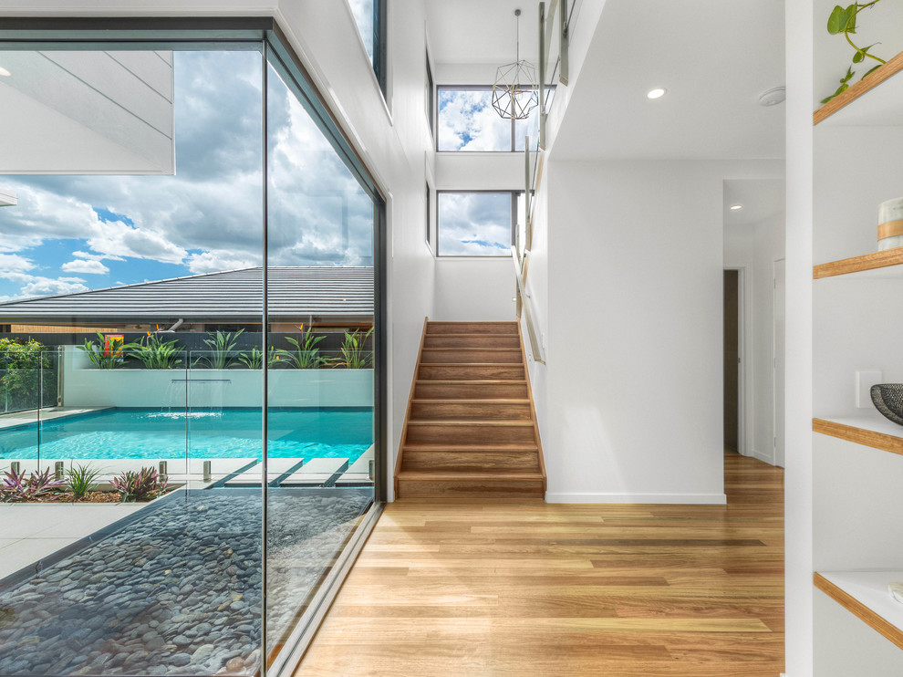 This is an example of a contemporary hallway in Brisbane with white walls and medium hardwood floors.