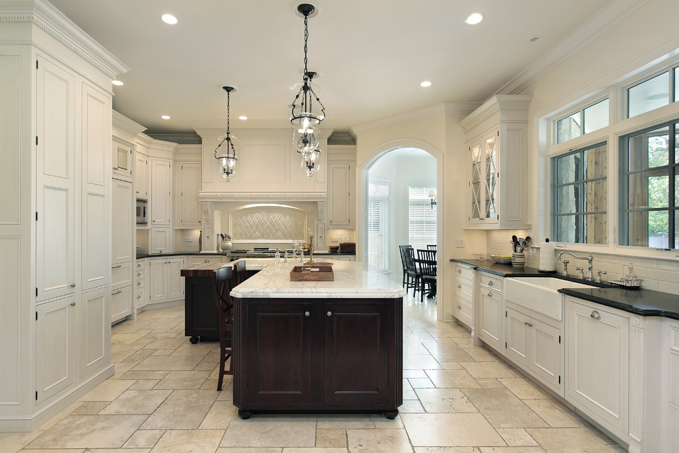 Inspiration for a huge transitional u-shaped travertine floor and beige floor eat-in kitchen remodel in Atlanta with a farmhouse sink, beaded inset cabinets, white cabinets, marble countertops, subway tile backsplash, paneled appliances and an island