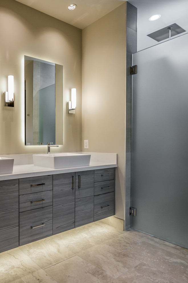 Expansive contemporary 3/4 bathroom in Phoenix with flat-panel cabinets, medium wood cabinets, a freestanding tub, an alcove shower, gray tile, porcelain tile, travertine floors, a vessel sink, quartzite benchtops, beige floor, a hinged shower door and grey benchtops.