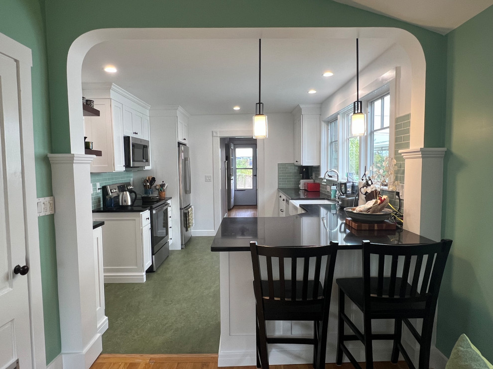 Design ideas for a mid-sized transitional l-shaped eat-in kitchen in Boston with a farmhouse sink, shaker cabinets, white cabinets, quartz benchtops, green splashback, ceramic splashback, stainless steel appliances, linoleum floors, a peninsula, green floor and black benchtop.