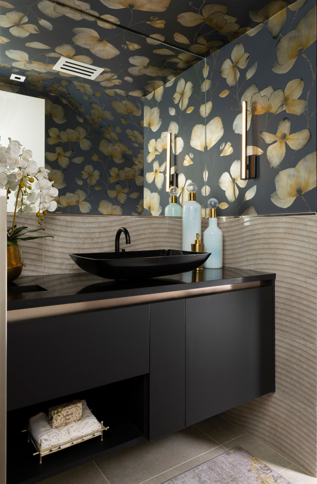 Inspiration for a mid-sized contemporary powder room in Other with flat-panel cabinets, black cabinets, beige tile, ceramic tile, beige walls, porcelain floors, a vessel sink, engineered quartz benchtops, grey floor, black benchtops, a floating vanity, wallpaper and wallpaper.