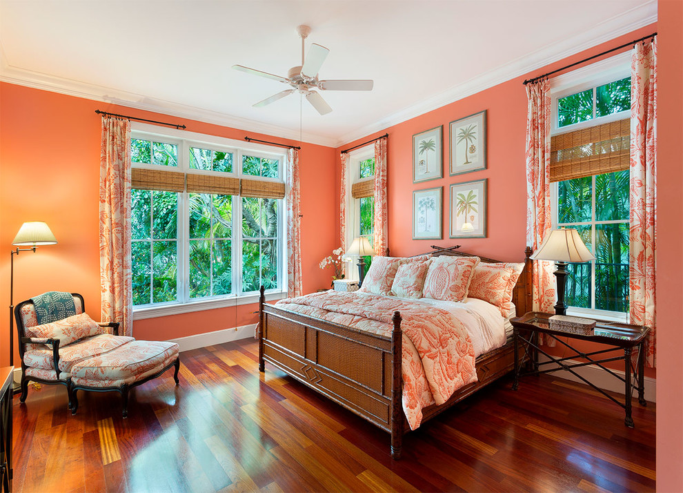 This is an example of a mid-sized tropical guest bedroom in Other with pink walls, medium hardwood floors, no fireplace and brown floor.