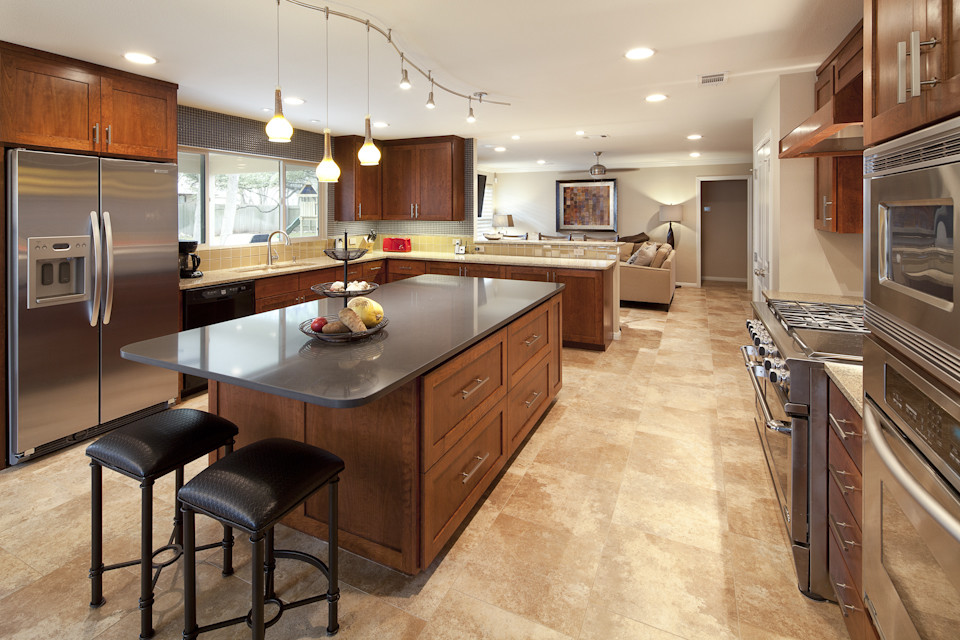 This is an example of a large transitional u-shaped eat-in kitchen in Austin with a double-bowl sink, shaker cabinets, medium wood cabinets, quartz benchtops, blue splashback, metal splashback, stainless steel appliances, travertine floors and with island.