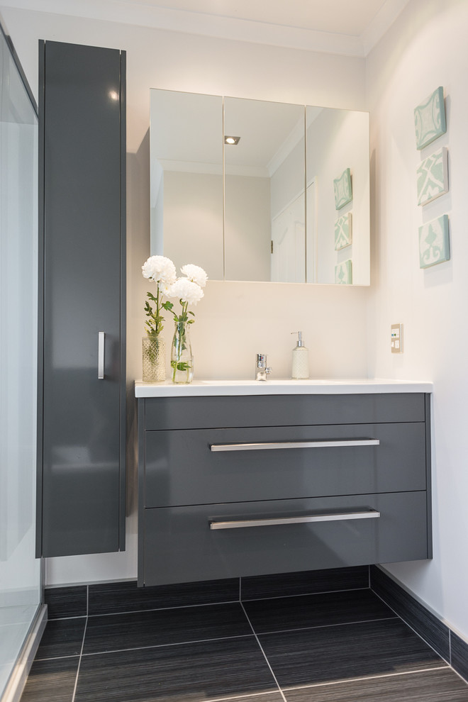 Design ideas for a small contemporary master bathroom in Auckland with flat-panel cabinets, grey cabinets, solid surface benchtops, a corner shower, grey walls, ceramic floors and a wall-mount sink.