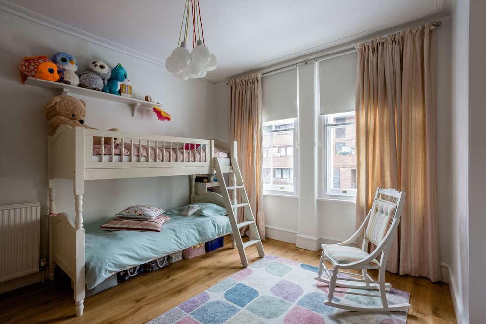 This is an example of a transitional kids' bedroom in London with white walls, medium hardwood floors and brown floor.