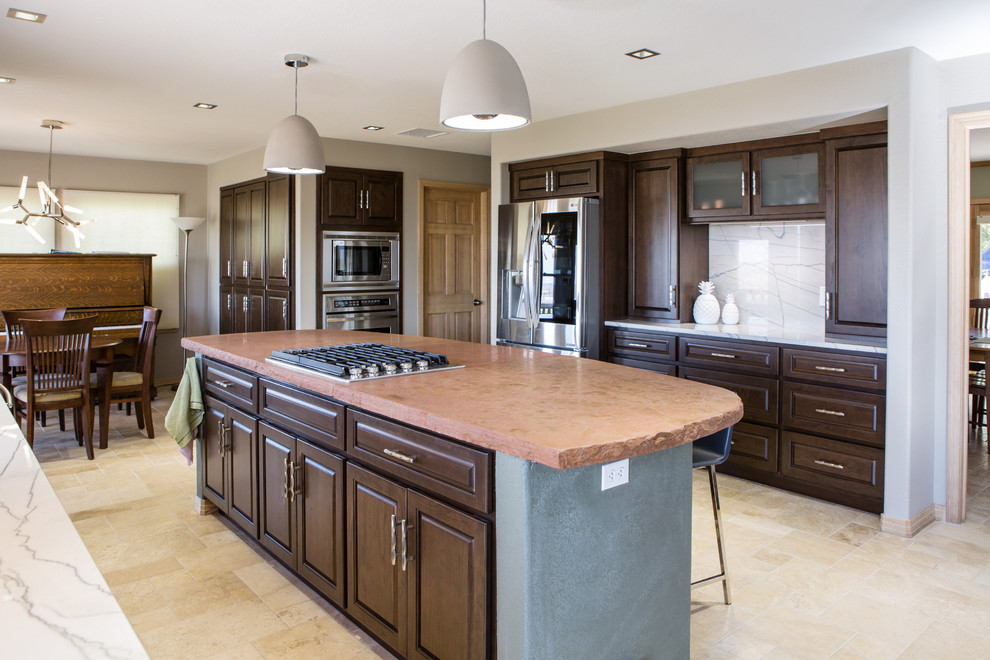 This is an example of a large transitional u-shaped eat-in kitchen in Denver with an undermount sink, raised-panel cabinets, dark wood cabinets, quartzite benchtops, white splashback, stone slab splashback, stainless steel appliances, travertine floors, with island, beige floor and white benchtop.