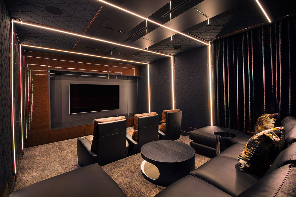 Photo of a contemporary enclosed home theatre with black walls, carpet, a built-in media wall and brown floor.
