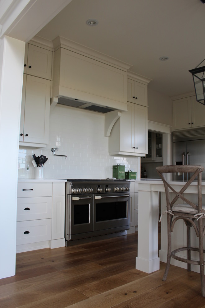 Inspiration for a large transitional l-shaped eat-in kitchen remodel in Toronto with an undermount sink, shaker cabinets, white cabinets, quartz countertops, white backsplash, stainless steel appliances and an island