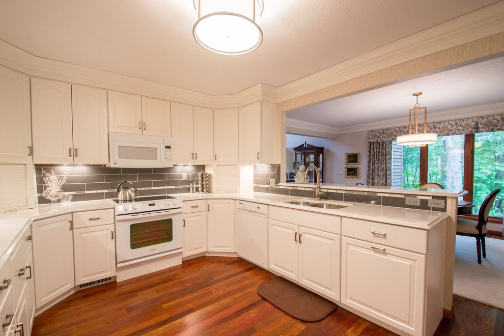 Mid-sized transitional u-shaped medium tone wood floor eat-in kitchen photo in Cedar Rapids with an undermount sink, white cabinets, quartzite countertops, gray backsplash, porcelain backsplash, white appliances and no island