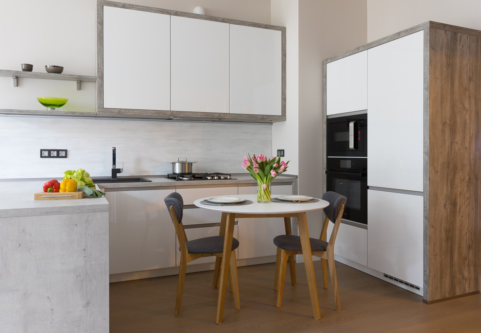 Design ideas for a contemporary u-shaped open plan kitchen in Other with a drop-in sink, flat-panel cabinets, white cabinets, grey splashback, black appliances, medium hardwood floors and no island.