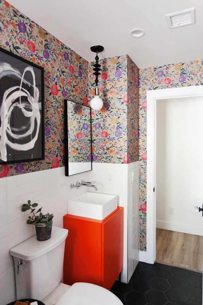 This is an example of a small eclectic 3/4 bathroom in Phoenix with flat-panel cabinets, orange cabinets, an open shower, white tile, ceramic tile, multi-coloured walls, ceramic floors, a vessel sink, laminate benchtops, black floor, an open shower, orange benchtops, a single vanity, a freestanding vanity and wallpaper.