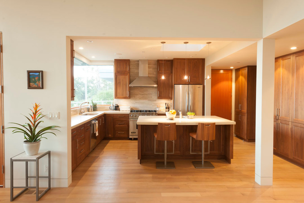 Design ideas for a mid-sized modern l-shaped open plan kitchen in Santa Barbara with raised-panel cabinets, medium wood cabinets, stainless steel appliances, light hardwood floors and with island.