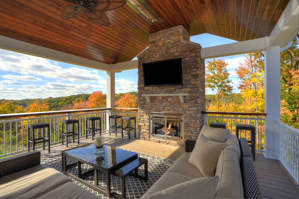 Example of a mid-sized mountain style backyard deck design with a fire pit and a roof extension