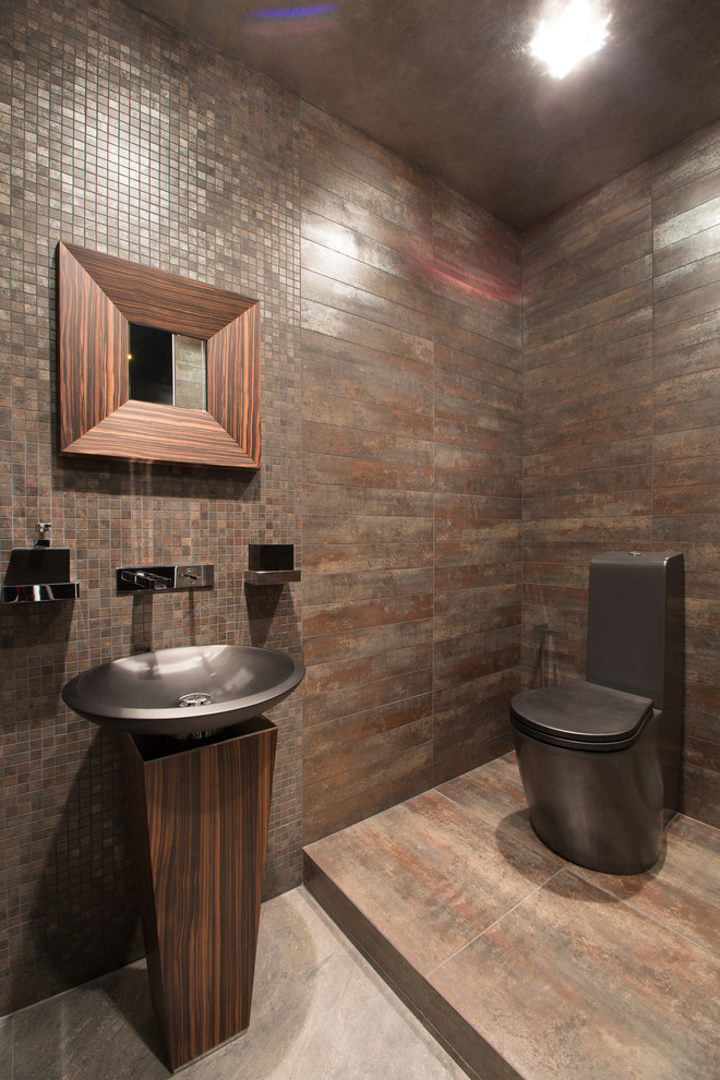 Contemporary powder room in Other with a one-piece toilet, brown tile, mosaic tile, a pedestal sink and brown walls.