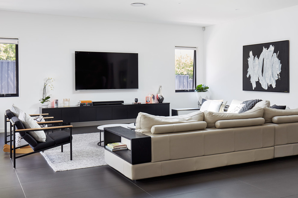 Contemporary living room in Sydney with white walls, a wall-mounted tv and grey floor.