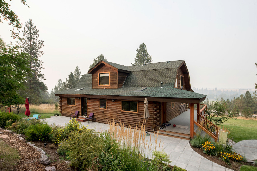На фото: трехэтажный, деревянный, коричневый дом среднего размера, из бревен в стиле рустика с мансардной крышей и крышей из гибкой черепицы