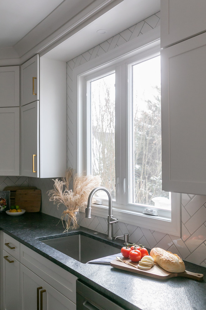 Inspiration for a large transitional l-shaped brown floor kitchen pantry remodel in Baltimore with a drop-in sink, shaker cabinets, white cabinets, quartz countertops, white backsplash, ceramic backsplash, stainless steel appliances, an island and white countertops