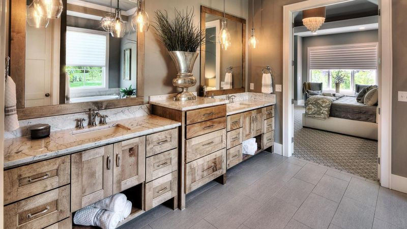 Inspiration for a large rustic master ceramic tile, gray floor and double-sink alcove bathtub remodel with furniture-like cabinets, medium tone wood cabinets, brown walls, an undermount sink, granite countertops, multicolored countertops and a built-in vanity