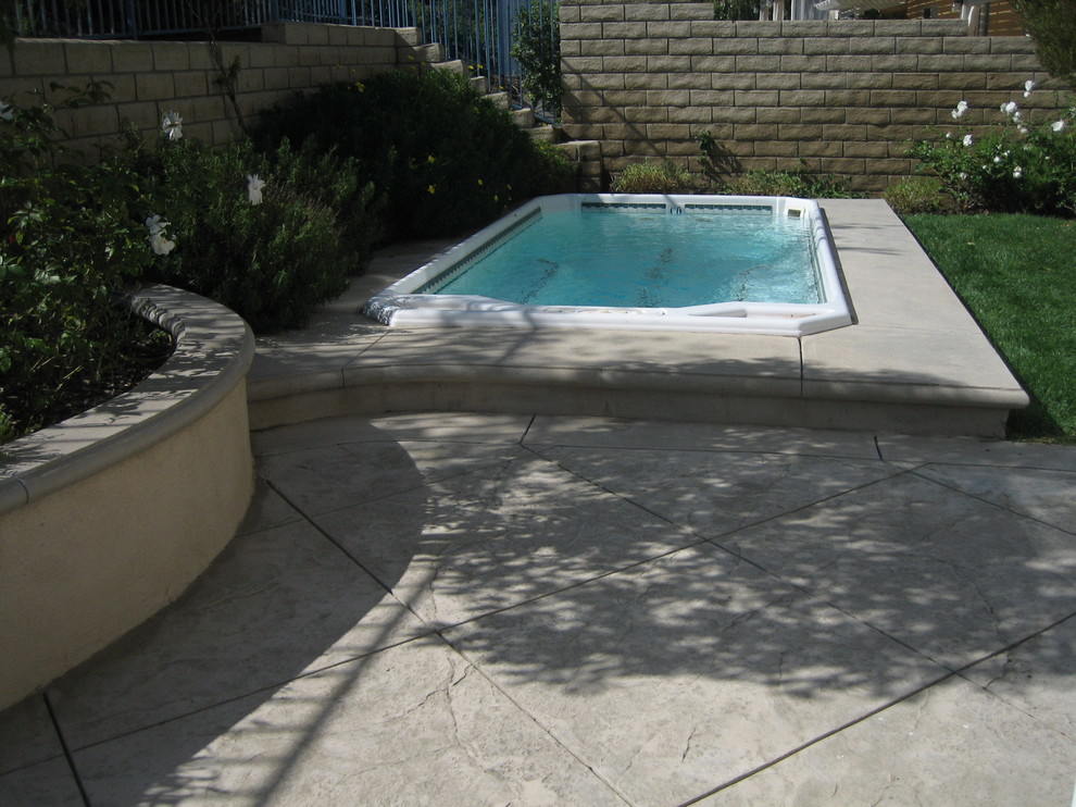 This is an example of a large traditional backyard rectangular aboveground pool in Los Angeles with natural stone pavers.