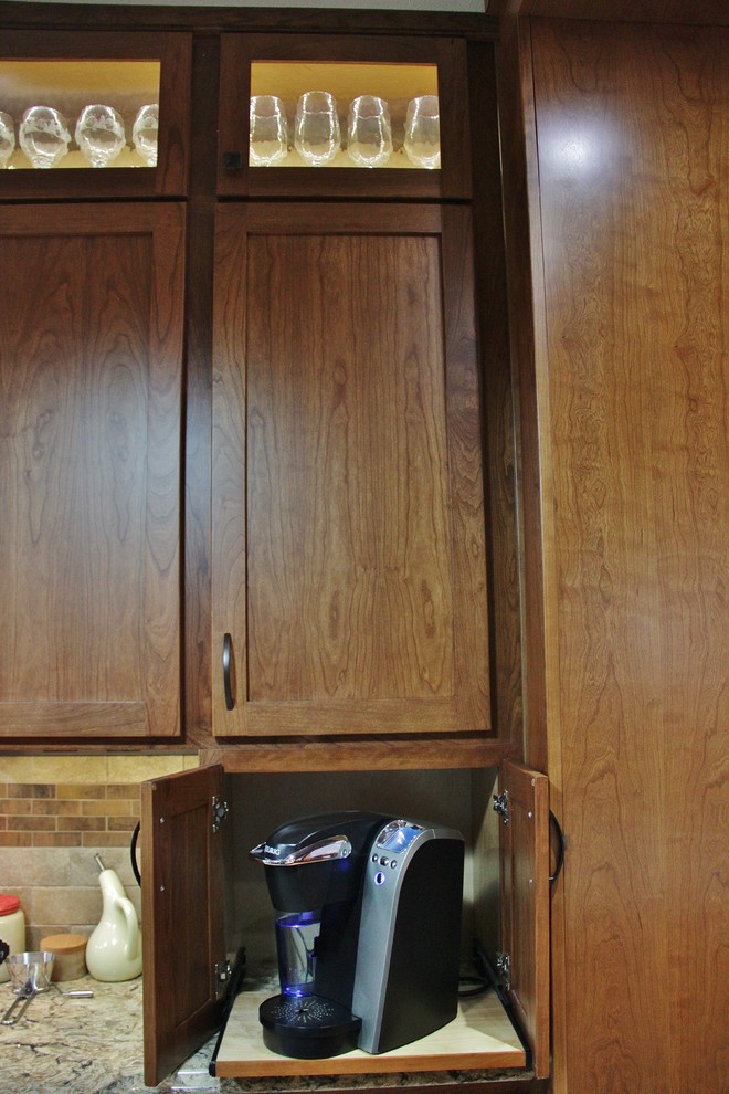 Example of a mid-sized transitional galley ceramic tile enclosed kitchen design with an undermount sink, shaker cabinets, medium tone wood cabinets, quartz countertops, beige backsplash, stone tile backsplash, stainless steel appliances and a peninsula
