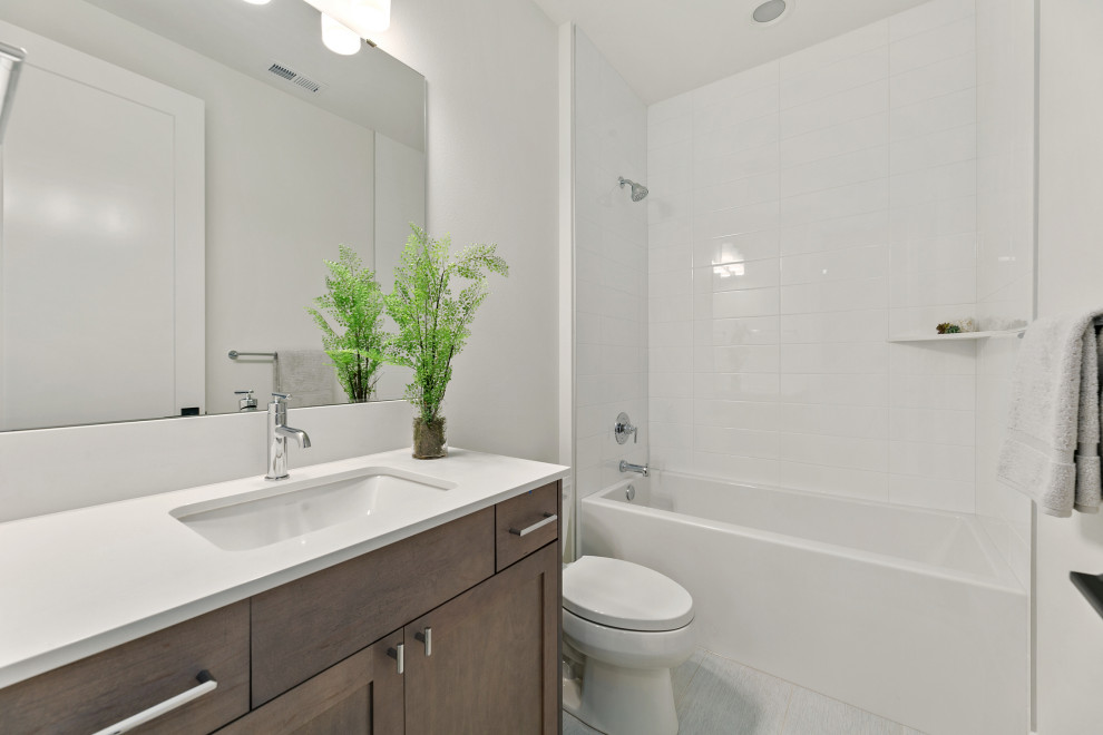 Photo of a mid-sized country kids bathroom in Seattle with recessed-panel cabinets, dark wood cabinets, a shower/bathtub combo, a one-piece toilet, white tile, subway tile, white walls, ceramic floors, an undermount sink, engineered quartz benchtops, grey floor, an open shower, white benchtops, a single vanity and a built-in vanity.