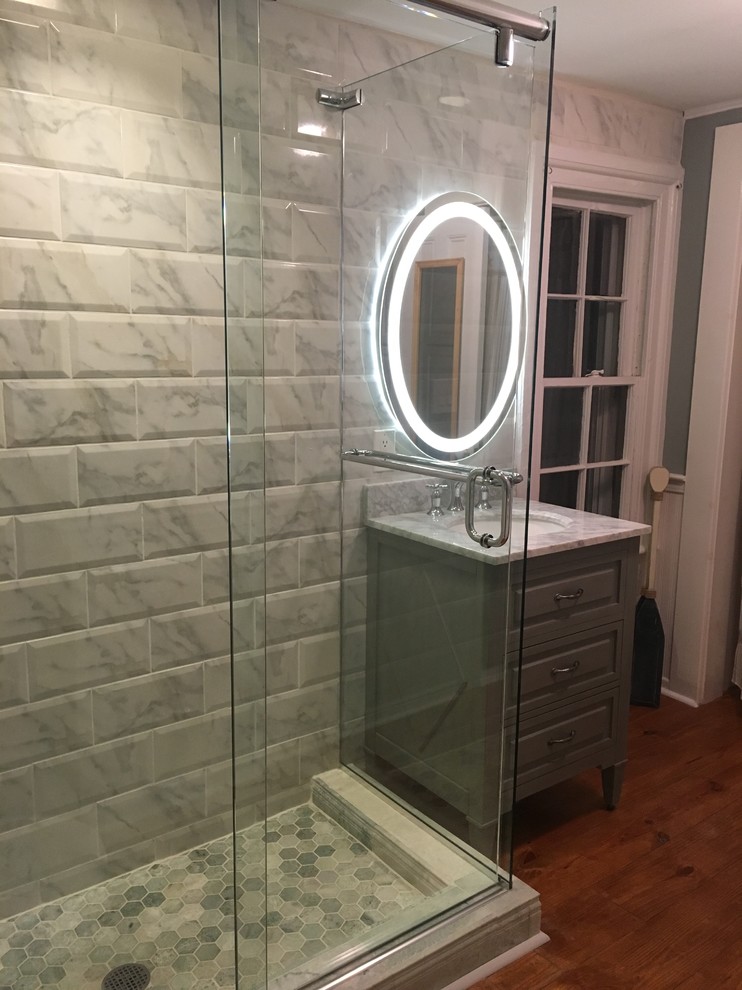 Photo of a mid-sized contemporary master bathroom in Providence with furniture-like cabinets, green cabinets, a corner shower, green tile, subway tile, green walls, medium hardwood floors, an undermount sink and marble benchtops.