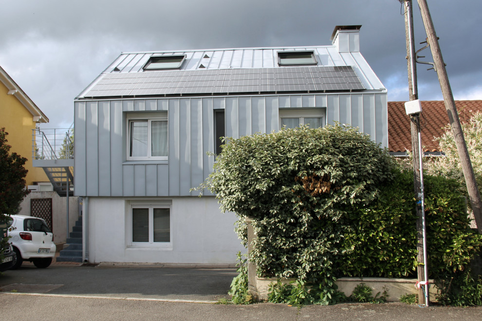 Inspiration for a mid-sized contemporary three-storey grey townhouse exterior in Nantes with metal siding, a gable roof, a metal roof, a grey roof and board and batten siding.