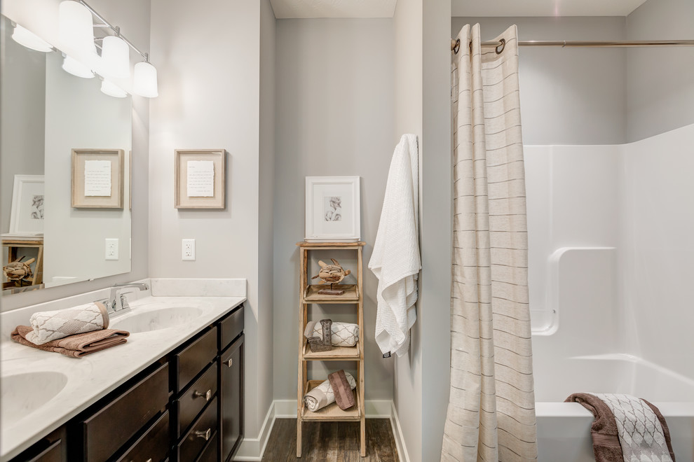 Mid-sized transitional master tub/shower combo photo with dark wood cabinets, a one-piece toilet, gray walls, an integrated sink and marble countertops